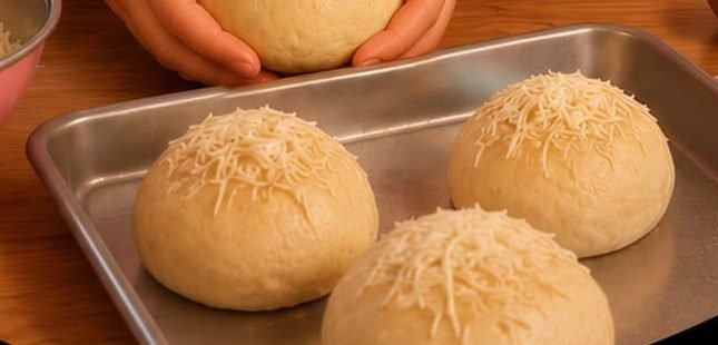 Assadeira com três pães delícia cobertos de queijo, prontos para o forno
